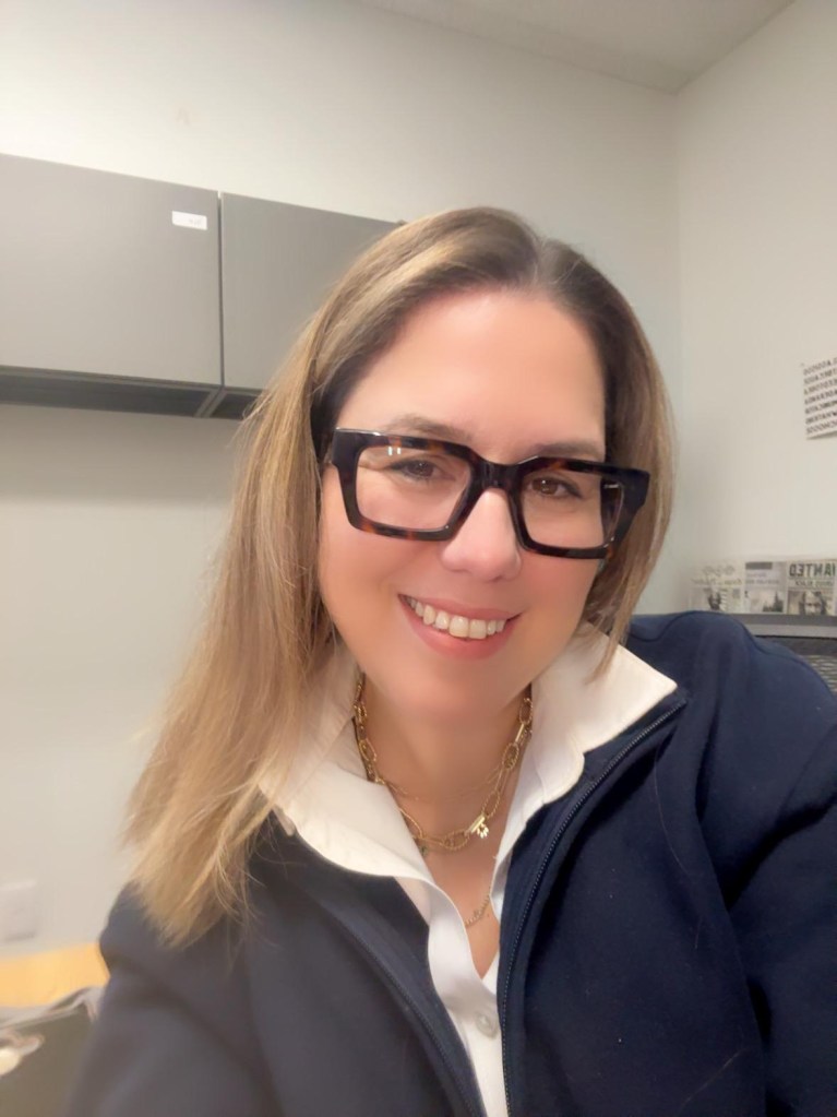 A photo of a blonde woman wearing glasses.